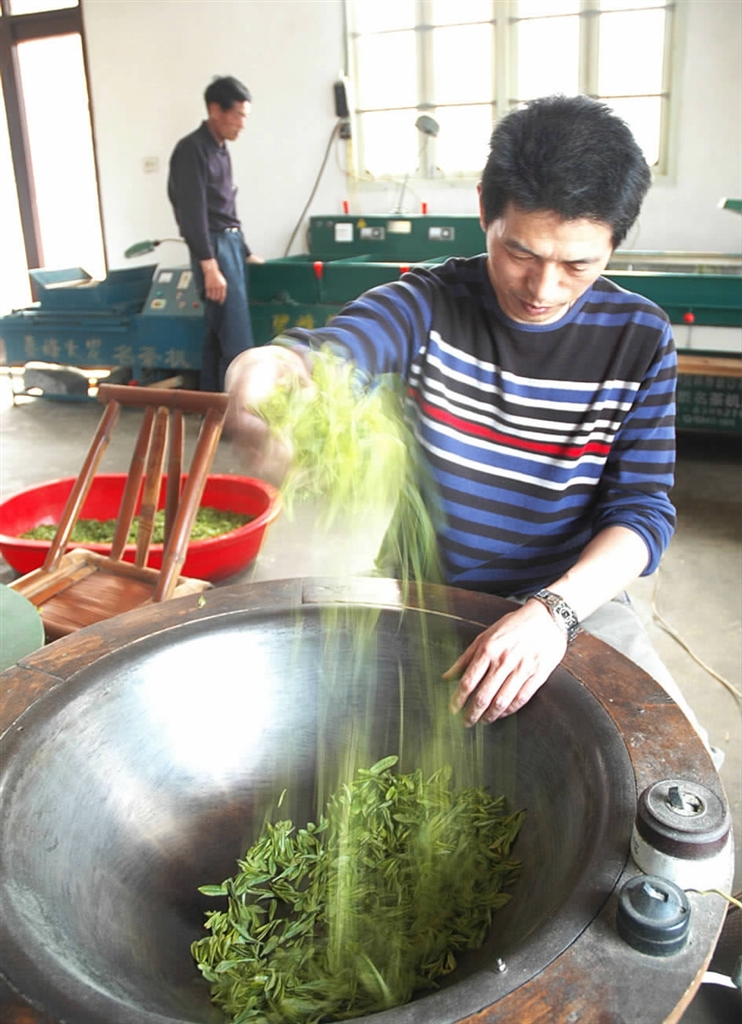 图为李水新在家里炒茶.