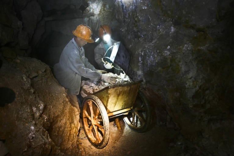 狭窄的矿洞里,采矿者以风钻,手凿,年复年,日复日地挖掘.