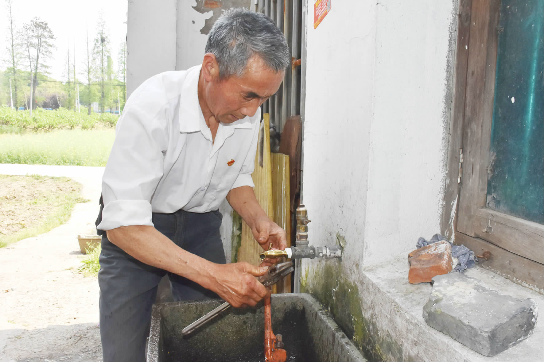 圖為沈炳泉正在修水龍頭.(圖片由越豐村提供)