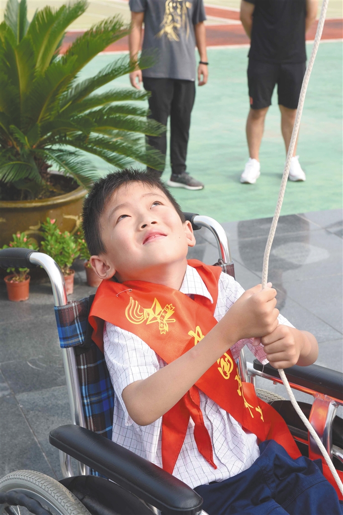 国歌响起,盐城市敬贤路实验小学二年级学生董昊鑫坐在轮椅上,拉动