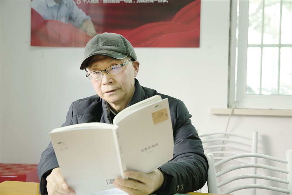 王根成手捧自己2011年出版的散文集《活着的美丽》.(沈慧摄)