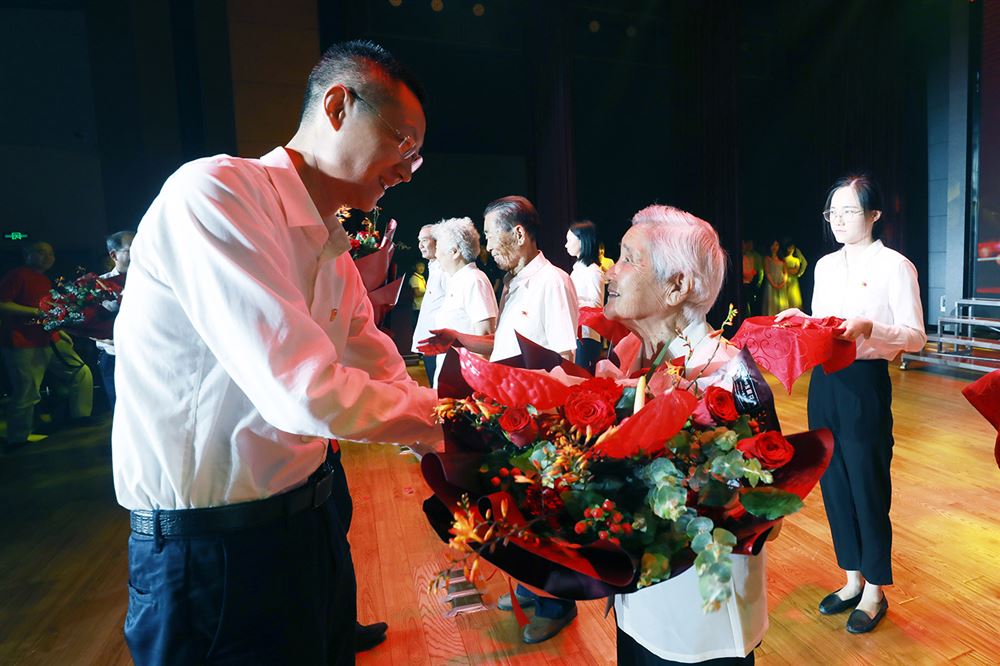 区委教育工委书记,区教育局局长季小峰为老党员送上鲜花和纪念章