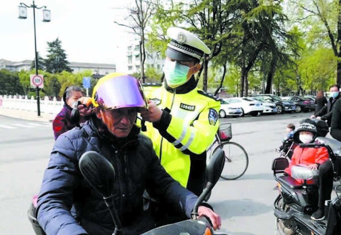 交警指导骑电动车市民正确佩戴头盔.